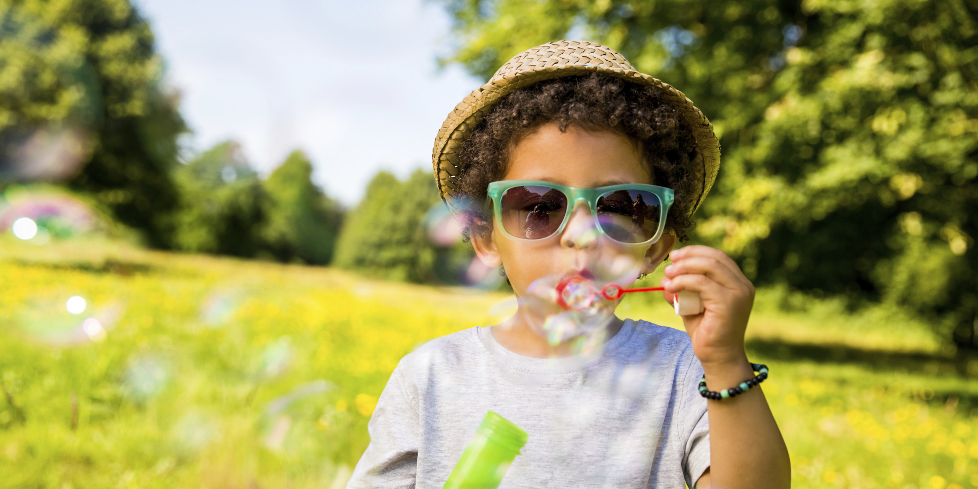 Child wearing a straw hat blowing bubbles