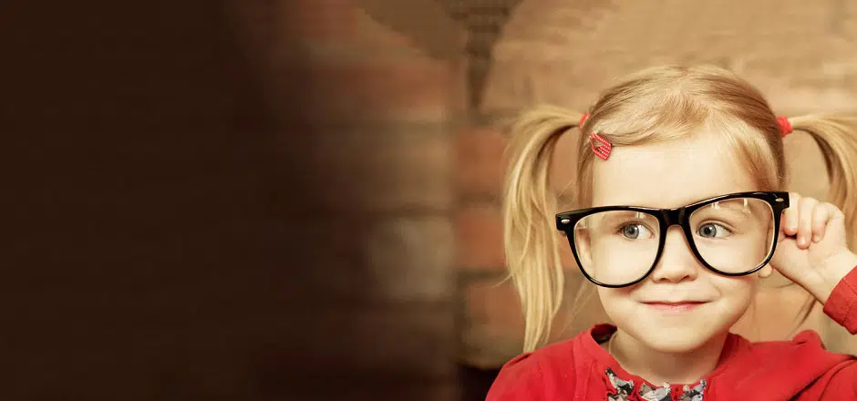 Girl with pigtails and adult glasses, smiling cheekily